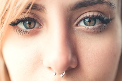A detailed close-up portrait of a woman with a nose ring and striking eyes, capturing natural beauty. Un portrait en gros plan détaillé d'une femme avec un piercing au nez et des yeux frappants, capturant la beauté naturelle.