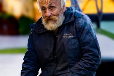 Portrait d'un homme âgé avec une barbe assis sur un banc de parc au crépuscule.