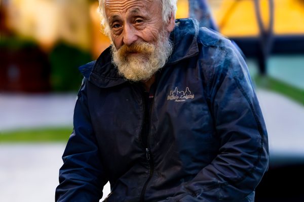Portrait d'un homme âgé avec une barbe assis sur un banc de parc au crépuscule.