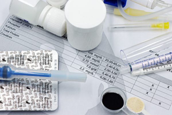 Vet supplies like syringes and medicines on blood test reports, suggesting medical care theme. Fournitures vétérinaires comme les seringues et les médicaments sur les rapports de tests sanguins, suggérant un thème de soins médicaux.