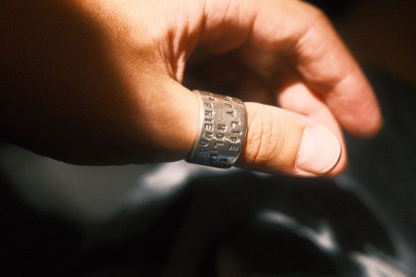 A close-up of a hand wearing an inscribed silver ring, captured in warm sunlight. Gros plan d'une main portant une bague en argent gravée, capturée à la lumière chaude du soleil.