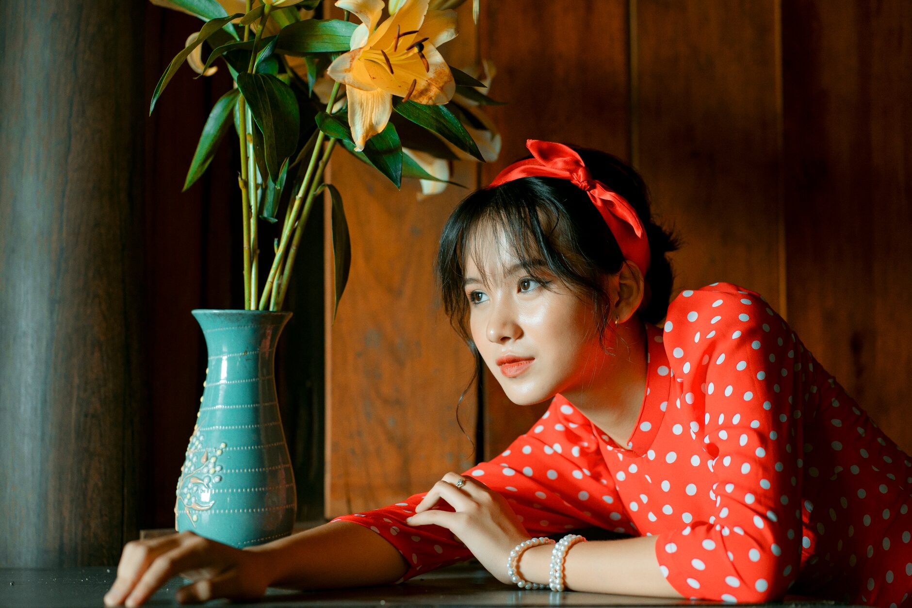 Femme aux cheveux bruns en tenue rouge accoudée à une table