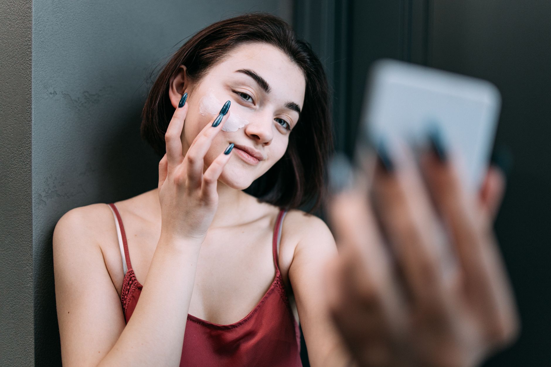 Jeune femme souriante appliquant une creme hydratante