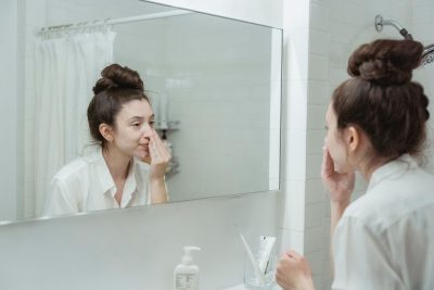 Femme appliquant une creme sur le visage dans sa salle de bain