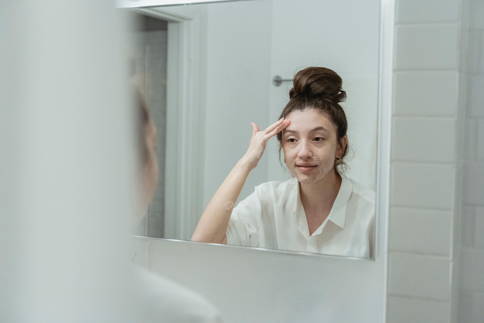 Femme appliquant une creme pour le visage devant son miroir